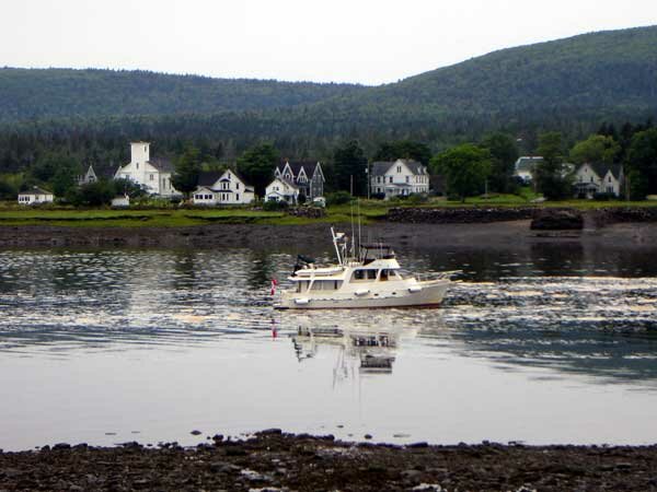 A boat steams up the Annapolis River past Annapolis Royal, NS